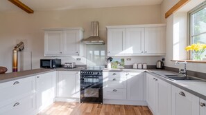 A modern kitchen with white cabinets, a stove, a microwave, and a sink.
