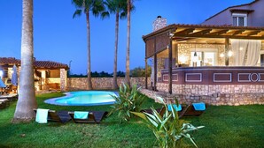 Zona de piscina amb gandules i una paret de pedra.