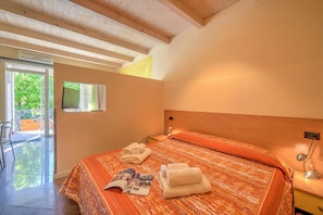 Een slaapkamer met een bed, een bedlampje, een raam en een deur naar een buitenruimte.