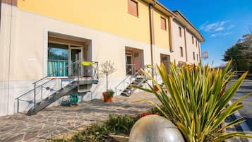 Un immeuble à la façade jaune, avec un escalier et une enseigne indiquant « Hôtel Albergato ».