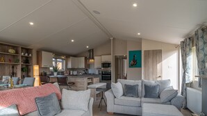 Una sala de estar moderna con un sofá gris, una mesa de centro y un comedor con una mesa de madera y sillas.