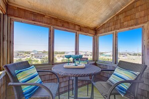 Relax in this serene outdoor seating area with a view of the surrounding neighborhood, featuring a round table and two comfortable wicker chairs.