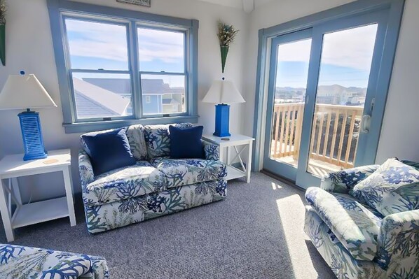 Relax in this inviting room with a balcony view, featuring a floral-patterned sofa set and two side tables with lamps.
