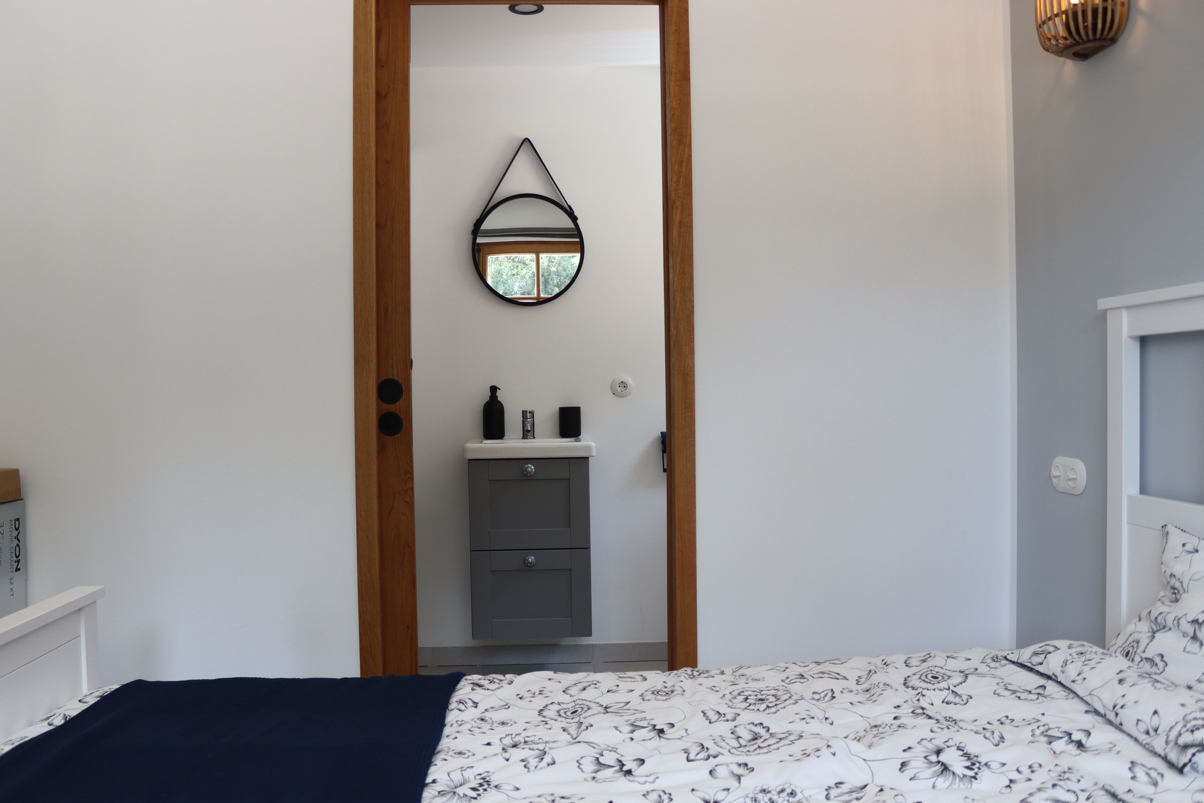 Una camera da letto con un letto, una cassettiera, uno specchio e una porta che dà su un'altra stanza.