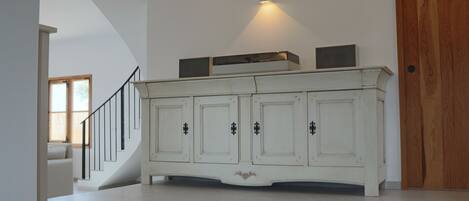 A spacious room with a white cabinet, a staircase, and a wooden door.
