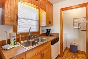 Kitchen features a double sink, coffee maker, dishwasher, and trash bin, with a window for natural light.