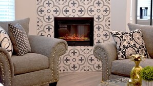 Ein Wohnzimmer mit Kamin, strukturierten Tapeten und zwei Sofas mit Zierkissen.