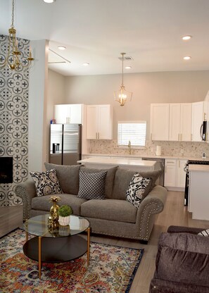 Relax in a cozy seating area with a round coffee table and vibrant rug. Enjoy a fully equipped kitchen with white cabinetry and oven.