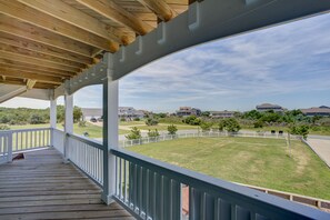 Relax on the covered outdoor deck with a view of the well-manicured lawn and surrounding buildings.