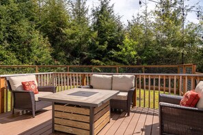 Relax on the deck surrounded by a dense forest, with a table and two chairs for a peaceful retreat.
