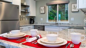A modern kitchen with white cabinets, a stainless steel refrigerator, and a granite countertop.