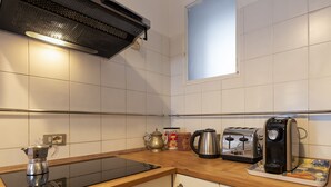 Een keuken met een zwart inductiefornuis, een koffiezetapparaat, een broodrooster en een waterkoker op een houten aanrecht.