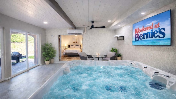 Un área moderna de piscina interior con un jacuzzi, un dormitorio con puerta corrediza de vidrio y un cartel que anuncia un fin de semana en Bernie's.