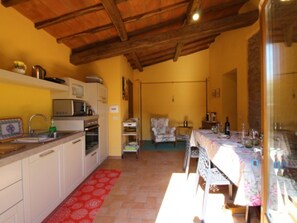 A compact kitchen with white cabinets, a microwave, and a sink. There is a dining area with a table set for two and a chair.