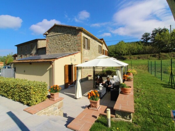 A stone house with a patio area, a white umbrella, and potted plants.