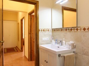 A bathroom with a white sink, mirror, and tiled walls.