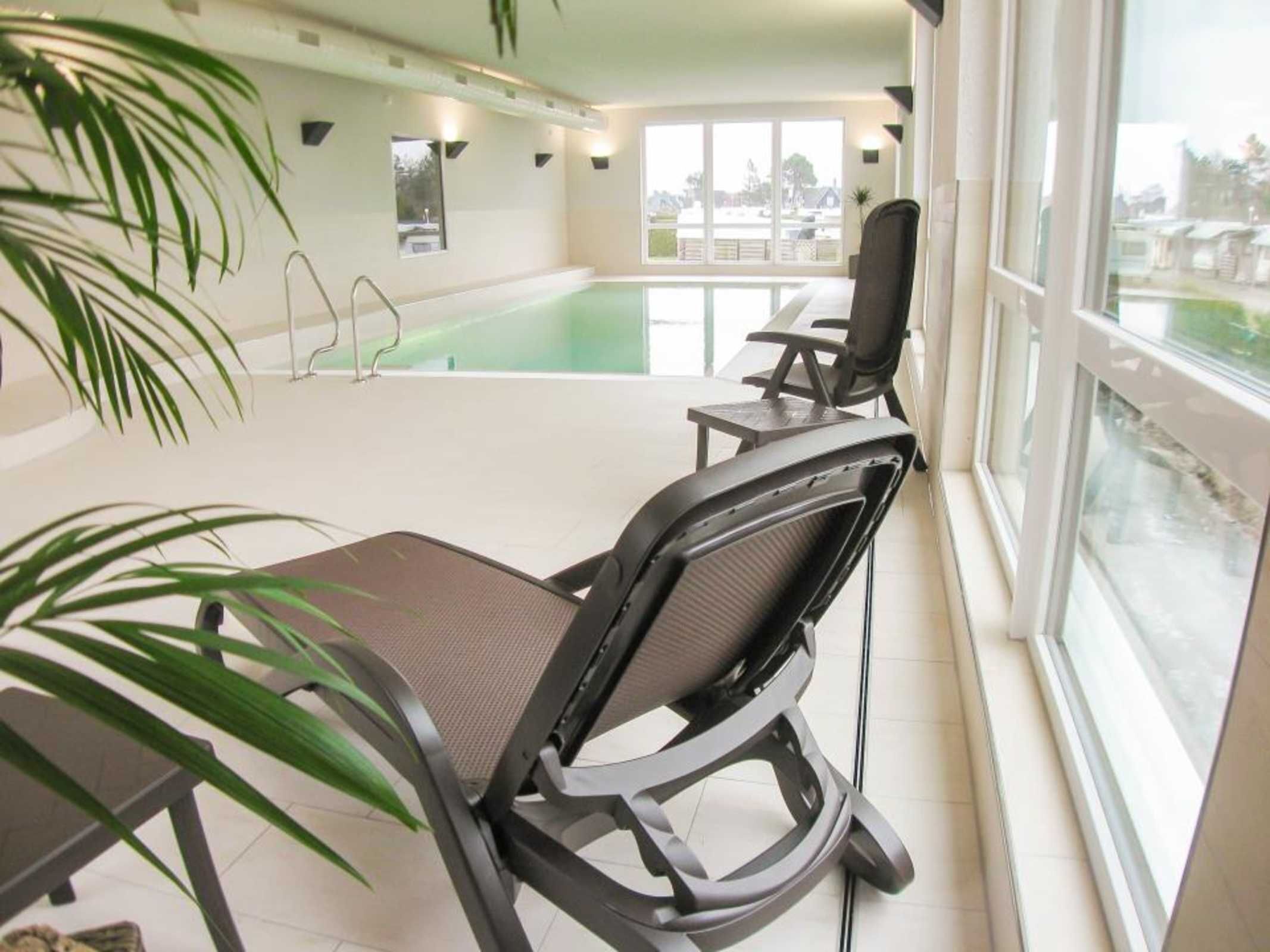 Ein Zimmer mit Pool, Stühlen, einem Tisch und einem großen Fenster.