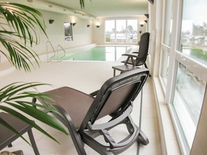 Une pièce avec une piscine, des chaises, une table et une grande fenêtre.