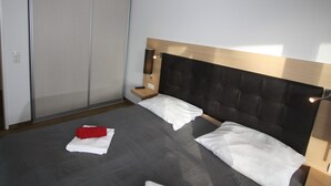 Ein Schlafzimmer mit Bett, Nachttisch, Wandlampe und Schrank mit Schiebetüren.
