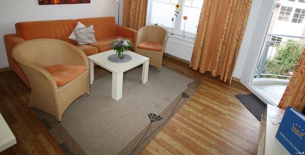 Un salon comprenant un canapé, des fauteuils, une table basse et une vue sur l’extérieur par une fenêtre.