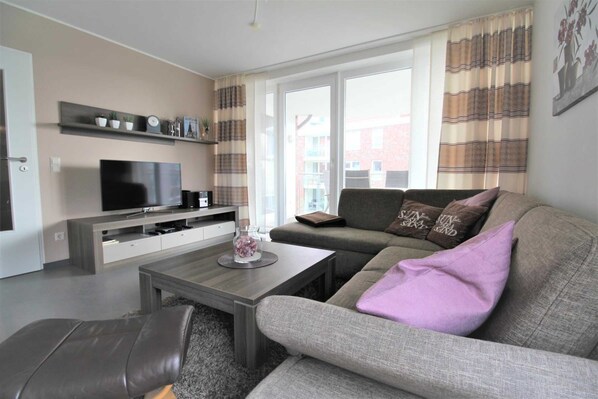 A modern living room with a sofa, a coffee table, and a television.