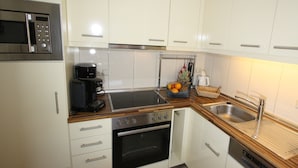 A modern kitchen with white cabinets, stainless steel appliances, a coffee maker, and a fruit basket. - HLI 1.11 up to 6 people 69sqm - Residenz Hohe Lith Cuxhaven (1.1) (Cuxhaven)