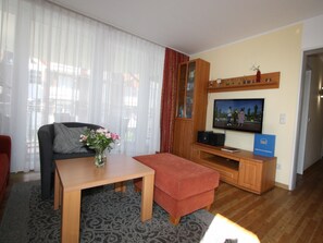 A living room with a sofa, a coffee table, a TV, and a cabinet.