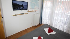 Una habitación de hotel con una cama, televisor montado en la pared, un mapa y una ventana con cortinas.