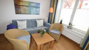 Una sala de estar con un sofá, dos sillones, una mesa de centro y un cuadro en la pared.
