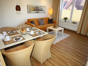Un salon meublé comprenant un canapé, une table à manger et des chaises en osier.