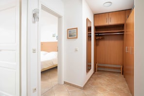 Hotellihuone, jossa on sänky, vaatekaappi ja pieni taulu seinällä.