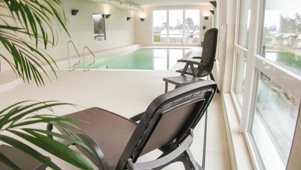 Ein Zimmer mit Pool, Stühlen, einem Tisch und einem großen Fenster.