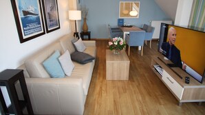 Ein modernes Wohnzimmer mit Sofa, Couchtisch, Fernseher und Essbereich.