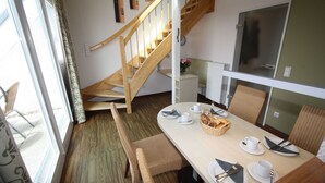 Ein Essbereich mit einer Holztreppe, Korbstühlen und einem Tisch für vier Personen.
