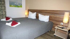 Ein Hotelzimmer mit einem großen Bett, zwei Kissen, einem Nachttisch mit Lampe und einem Bild an der Wand.