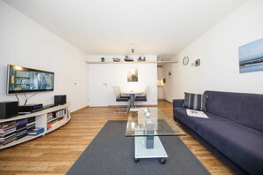 Un salon moderne avec un téléviseur à écran plat, un canapé, une table basse et une bibliothèque.