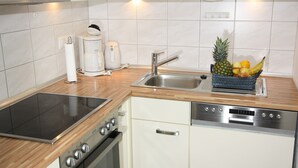 A modern kitchen with a built-in oven, dishwasher, and a stainless steel sink.