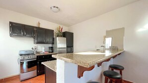 Una cocina con estufa, refrigerador, microondas y encimera de granito.