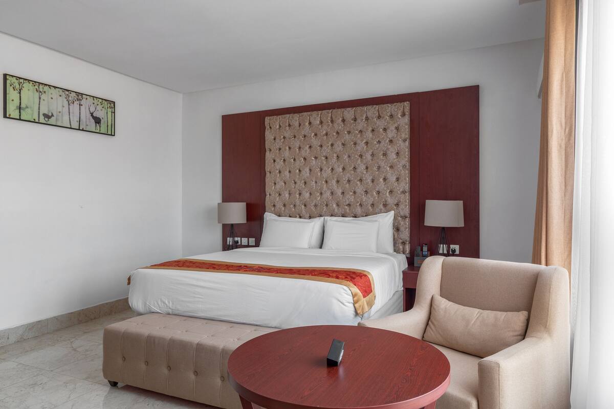 Ein Hotelzimmer mit einem Bett, einem Sessel, einem runden Tisch und einem Wandbild.