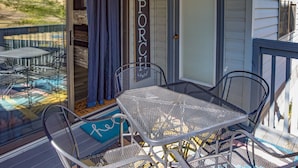 Un portico coperto con un tavolo e sedie in metallo, un cartello con la scritta 'Benvenuti nel NOSTRO PORCH' e un cartello 'Vietato Fumare' appeso al muro.