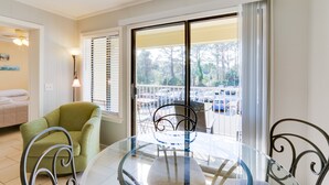 A room with a glass table, chairs, a green armchair, a balcony with a view of a parking lot. - Beachy Getaway w/ Balcony on Hilton Head Island! (Hilton Head Island)