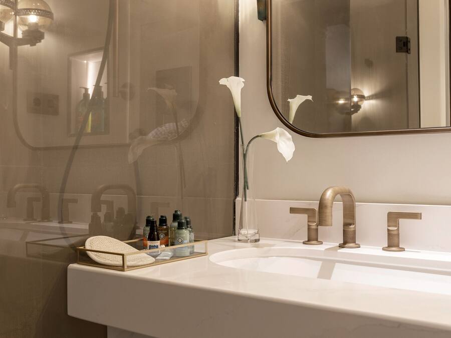 Un baño moderno con un espejo grande, un lavamanos blanco y una cabina de ducha de vidrio.