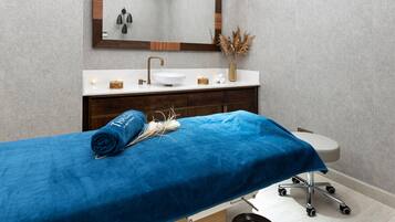 A modern bathroom with a large mirror, a white sink, and a blue towel on a bed.