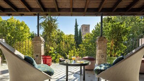 An outdoor patio with two cushioned chairs, a round table, and a view of a historic tower. -  Seda Club Hotel – Small Luxury Hotel (Granada)