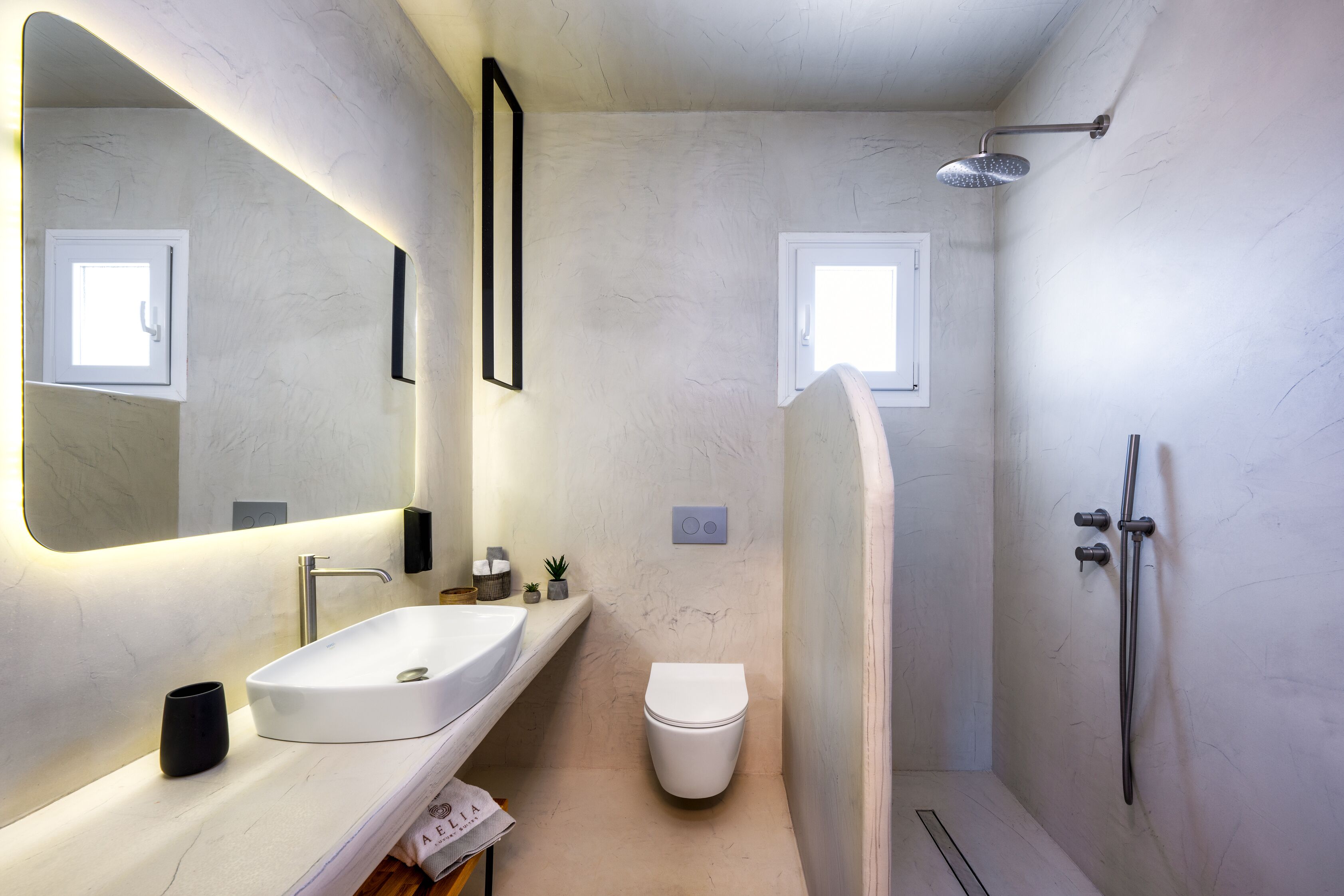 Ein modernes Badezimmer mit einem großen Spiegel, einem Waschbecken, einer Toilette und einer Dusche.