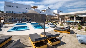 A rooftop pool area with multiple sun loungers and a central swimming pool. - Aelia Luxury Suites (Santorini)