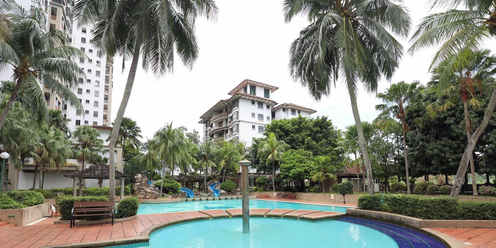 Una piscina rodeada de palmeras y un edificio de varios pisos.
