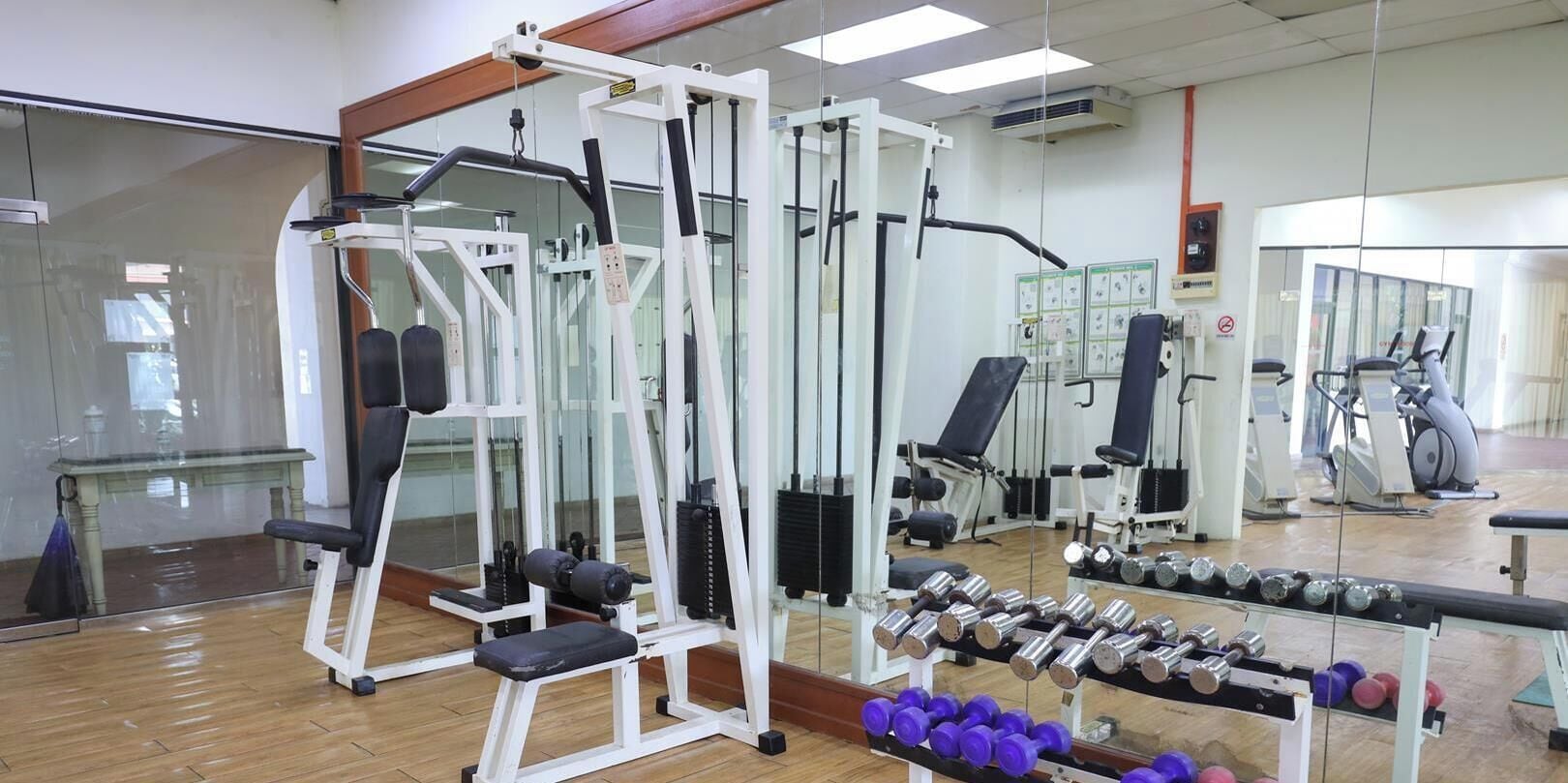 A gym with various exercise equipment, including a squat rack, benches, and dumbbells.