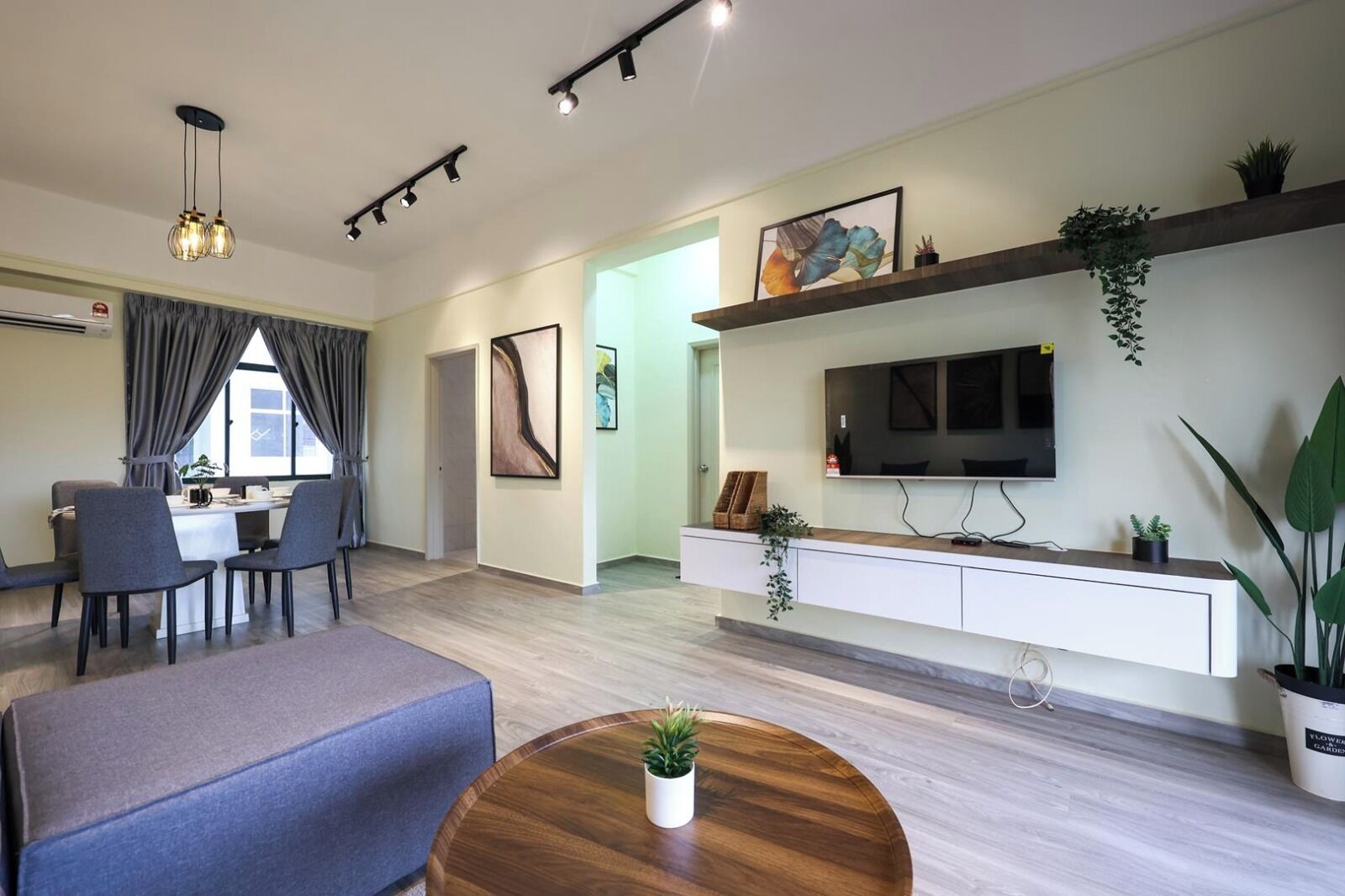 Un salon moderne doté d’un téléviseur à écran plat, d’un coin repas avec une table et des chaises, et d’un espace détente avec un canapé et une table basse.