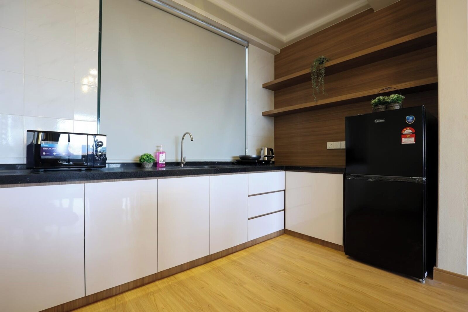 A modern kitchen with white cabinets, a black refrigerator, and a microwave on the countertop.